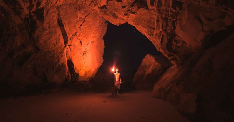 Torch Shadow - Person Standing and Holding Lamp Inside Cave