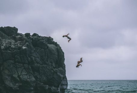 Cliff Jump - Two People Jumping on Body of Water