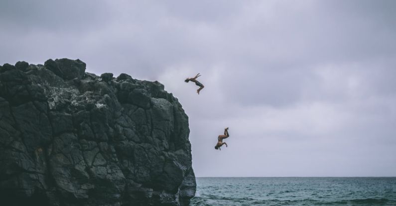 Cliff Jump - Two People Jumping on Body of Water