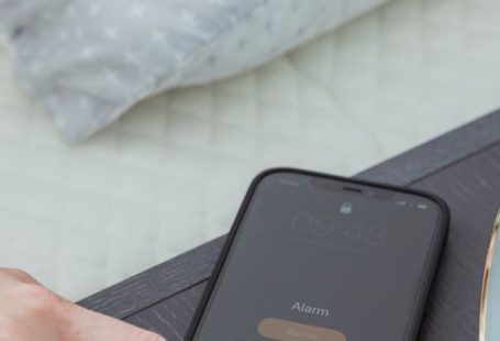 Phone Off - From above of hand of crop anonymous female turning off alarm on mobile phone in bedroom in morning time