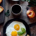 Fork Apple - Top view of fried eggs with mint in pan near fruits and bread on wooden table