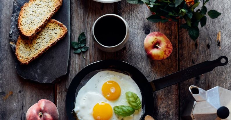 Fork Apple - Top view of fried eggs with mint in pan near fruits and bread on wooden table