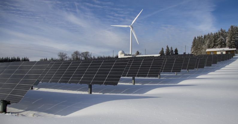 Wind Solar - Solar Panels on Snow With Windmill Under Clear Day Sky