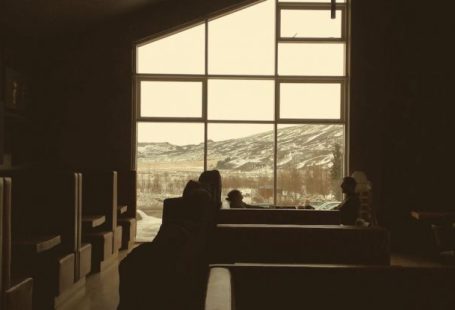Ceiling Break - Dark brown tables and couches under angled ceiling in empty dark cafe with mountain through big window