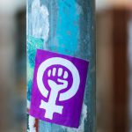 Paint Fist - Shabby aged blue metal street pole with rebel fist sticker and marks located on pavement