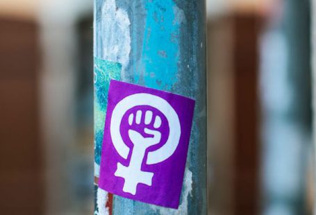 Paint Fist - Shabby aged blue metal street pole with rebel fist sticker and marks located on pavement