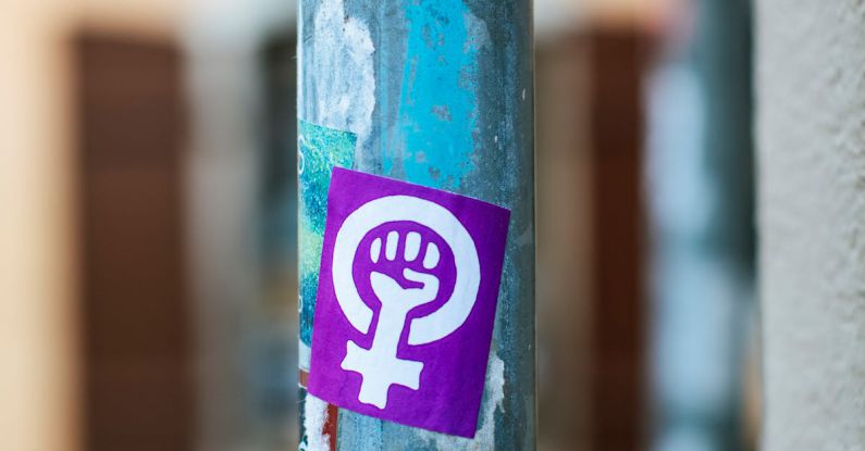 Paint Fist - Shabby aged blue metal street pole with rebel fist sticker and marks located on pavement