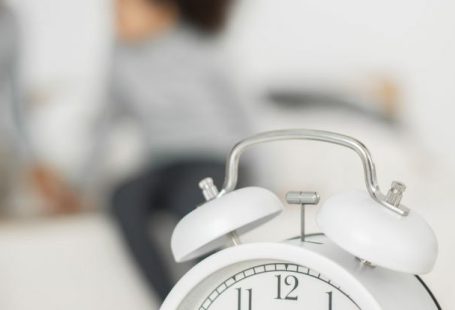 Clock Generations - Retro styled alarm clock placed on table in bedroom near unrecognizable African American little child playing with mother