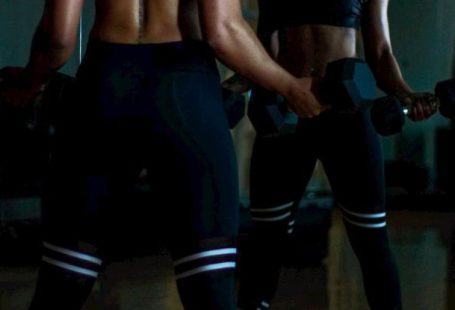 Mirror Body - Woman Lifting Two Dumbells on Both Hands in Front of Mirror