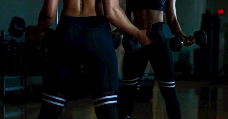 Mirror Body - Woman Lifting Two Dumbells on Both Hands in Front of Mirror