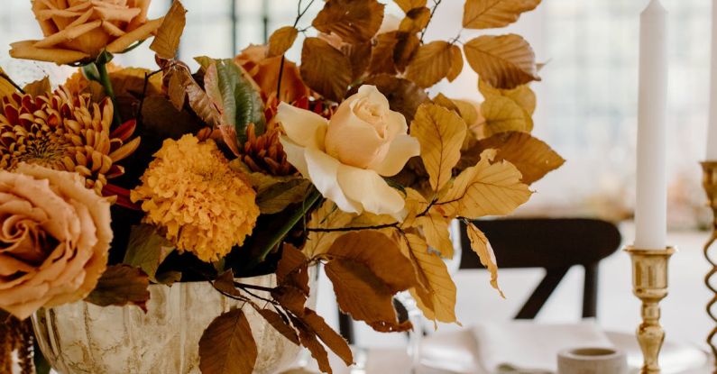 Fork Leaf - Elegant floral composition in vase placed on white table with ceramic plates and golden cutlery during festive banquet