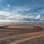 Footprint Earth - A circular track on the beach with a large sand dune