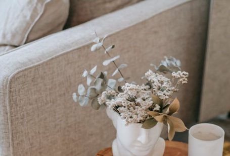 Mirror Nature - Cozy sofa with decorative cushions near stump with books and blooming flowers in vase in house room