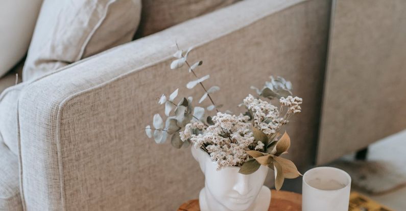 Mirror Nature - Cozy sofa with decorative cushions near stump with books and blooming flowers in vase in house room
