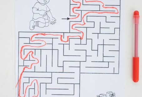 Paint Brain - Top view of solved labyrinth test with little boy and boots painted on paper placed on white desk with red pen